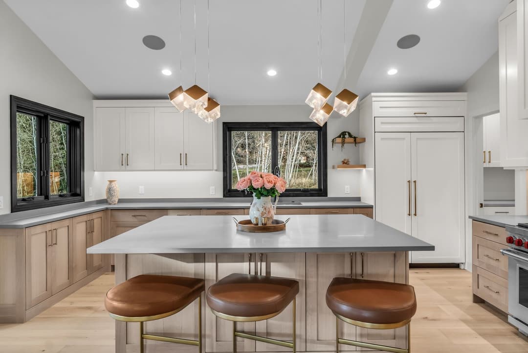 Modern kitchen with wooden cabinetry, quartz island, and elegant pendant lights.