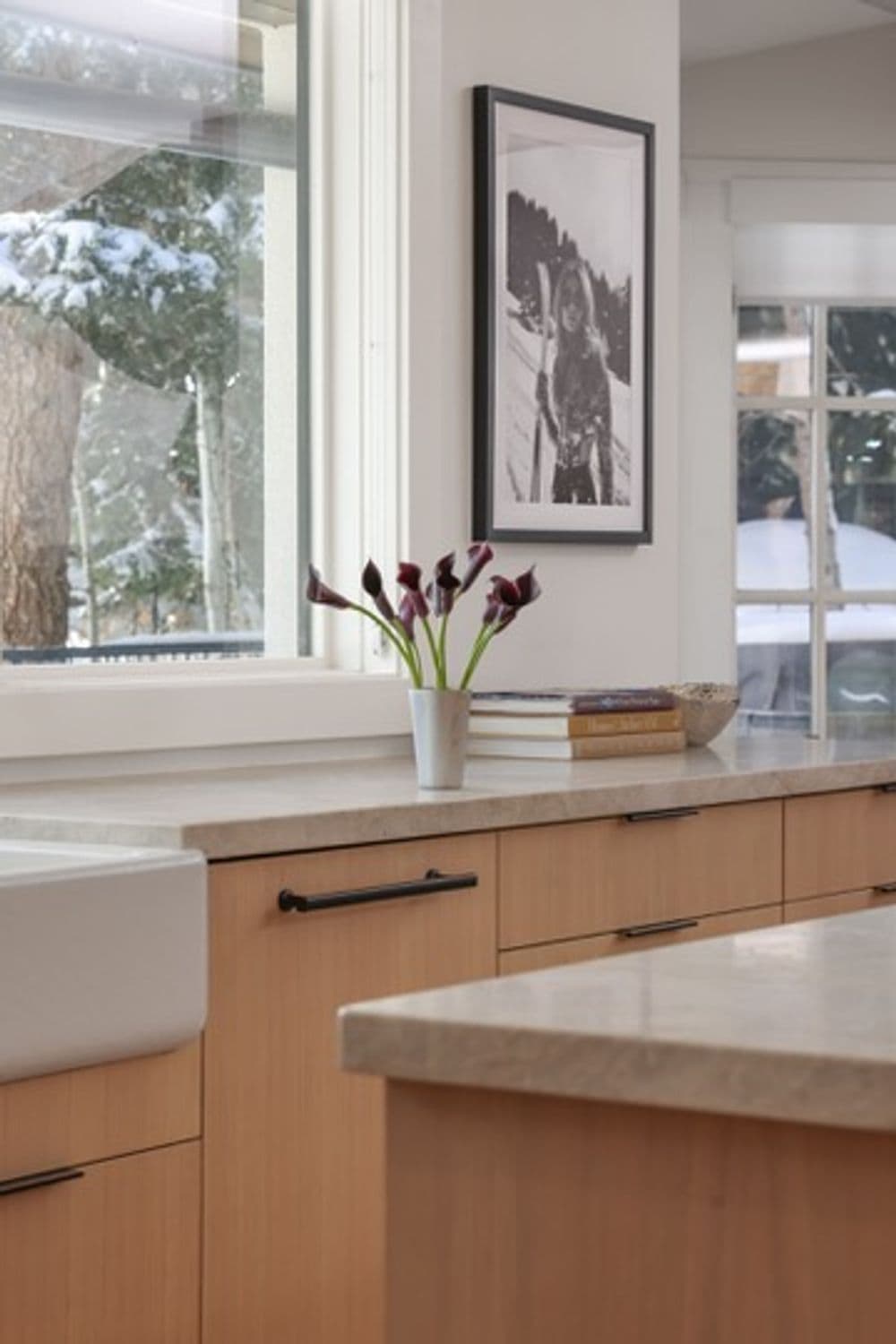Modern kitchen with a vase of purple calla lilies on the counter and a framed photo on the wall.