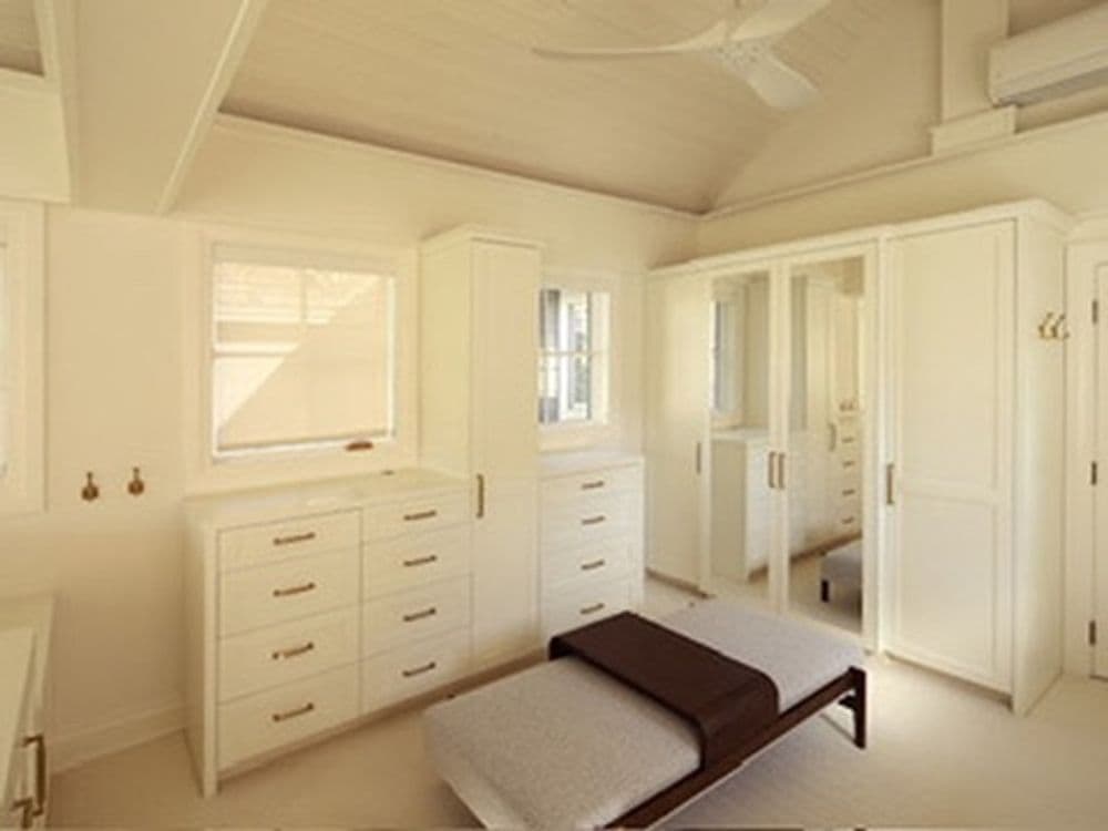 Modern minimalist bedroom with white cabinetry and a sleek daybed, featuring natural light.