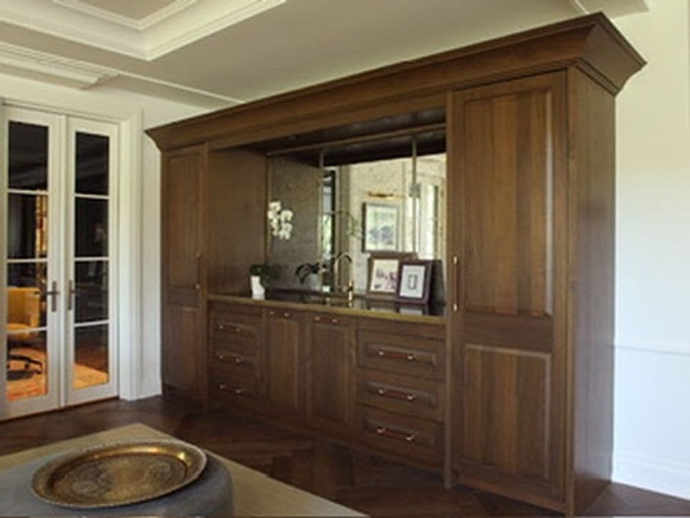 Elegant wooden cabinetry with mirrored backing in a modern living space interior design.