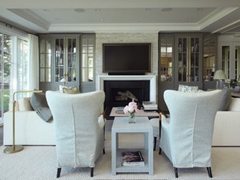 Modern living room with gray wingback chairs, coffee table, and large TV above the fireplace.