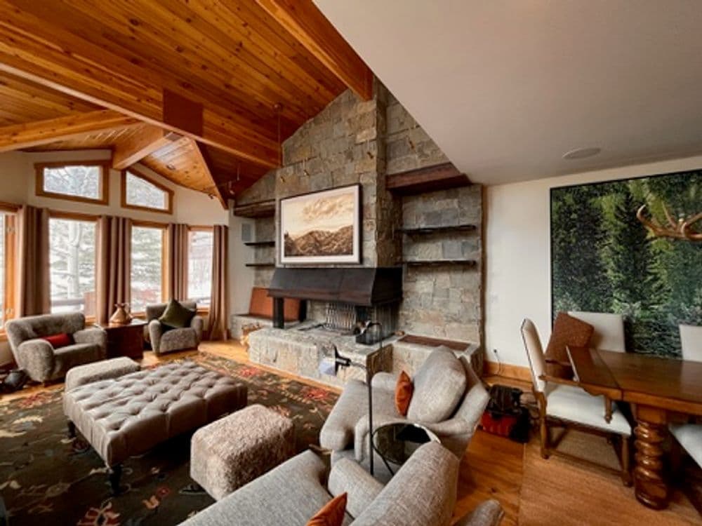Cozy living room with rustic wooden beams, stone fireplace, and modern furniture designs.