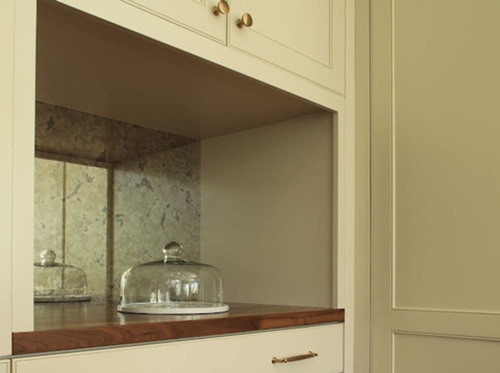 Stylish kitchen cabinetry with a glass dome, wood countertop, and elegant stone backsplash.