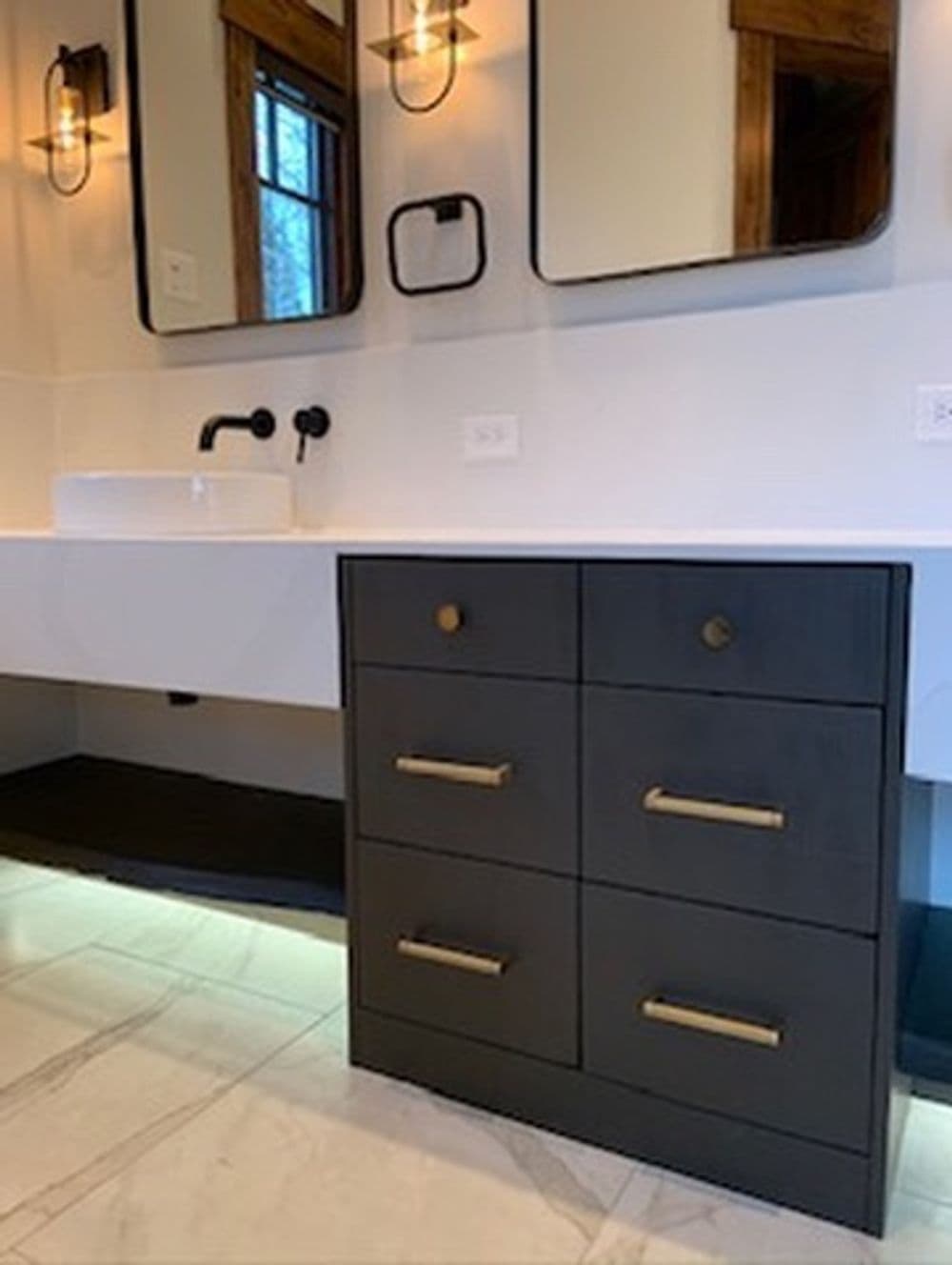 Modern bathroom with double mirrors, black vanity unit, gold handles, and elegant lighting.