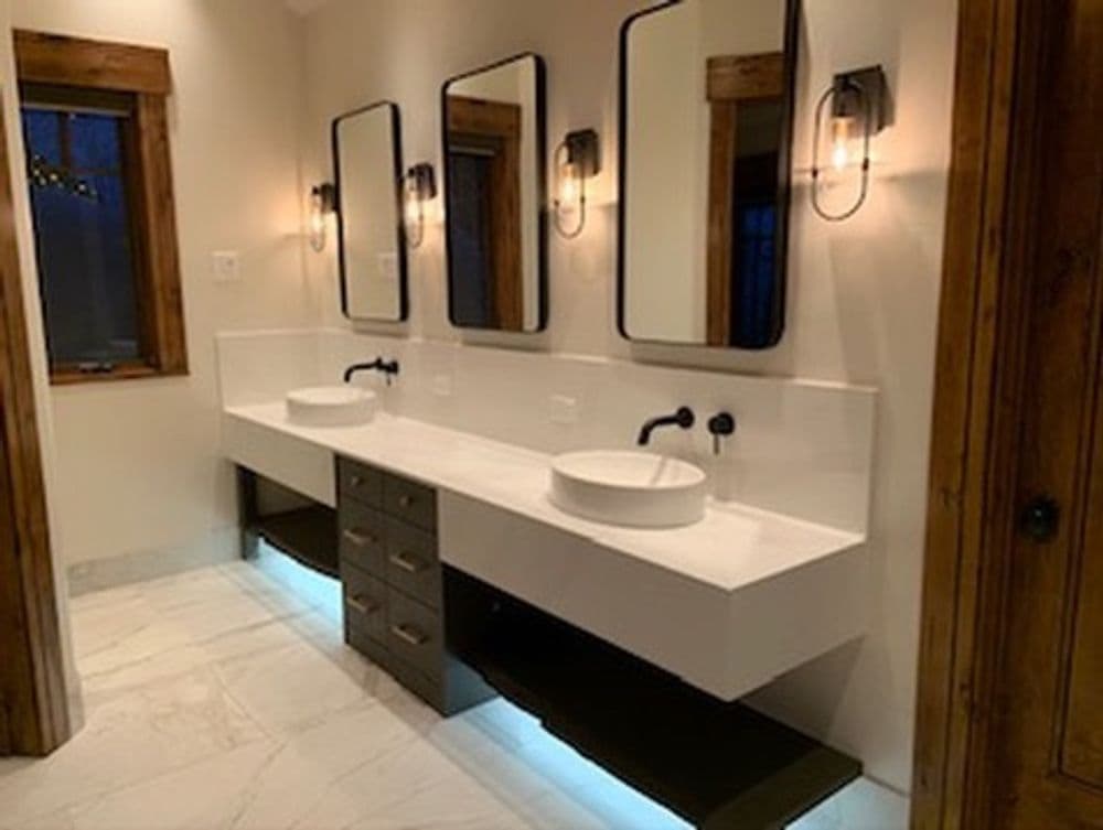 Modern bathroom with double vessel sinks, black fixtures, and stylish lighting.