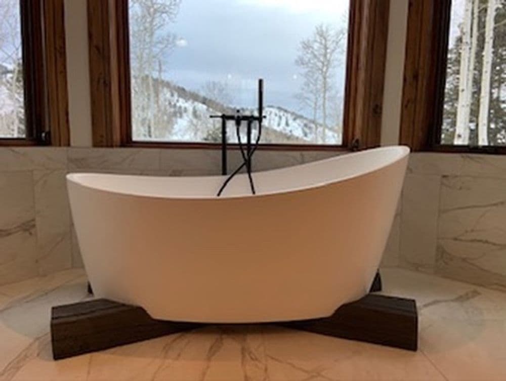 Modern freestanding bathtub with scenic mountain view through large windows. Elegant design.