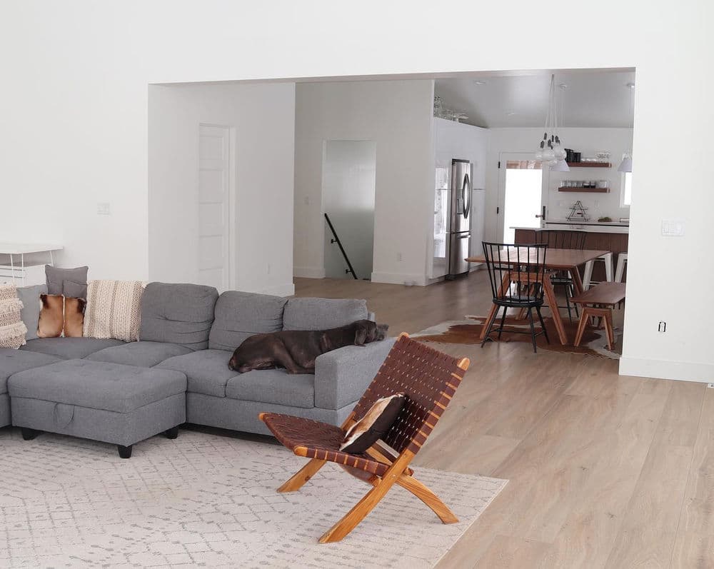 Modern living room featuring a gray sectional sofa, a brown chair, and an open dining area.
