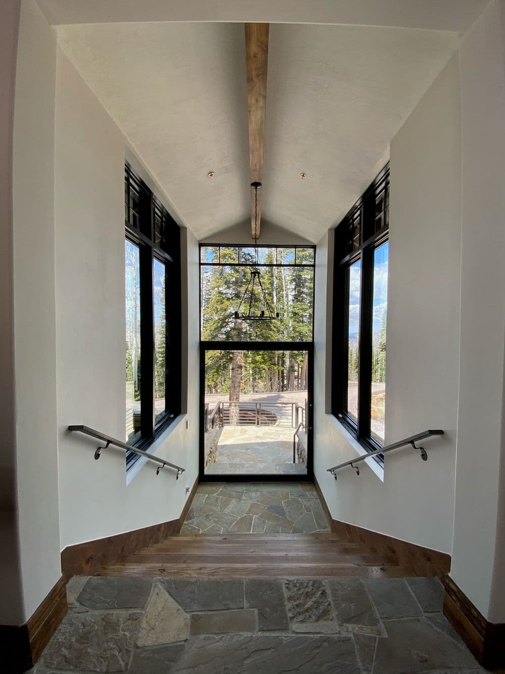 Modern staircase leading to outdoor view with large windows and natural light.