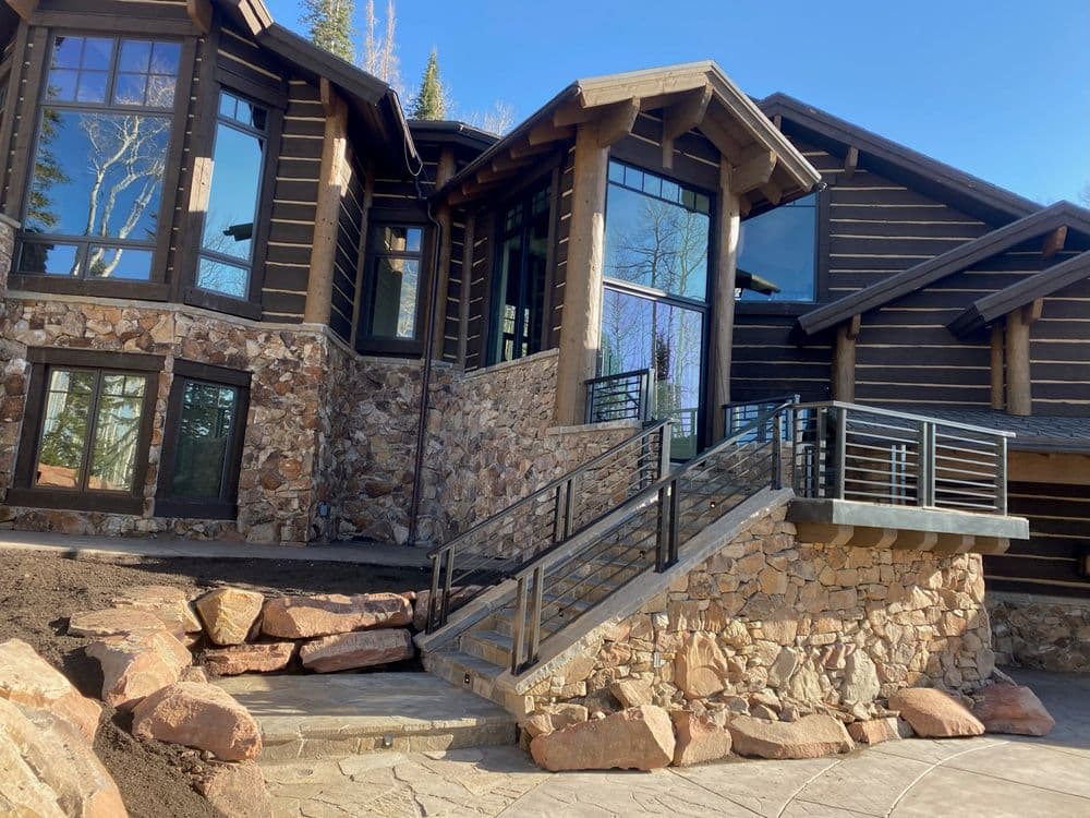 Modern mountain lodge with stone facade and accessible ramp in sunny outdoor setting.
