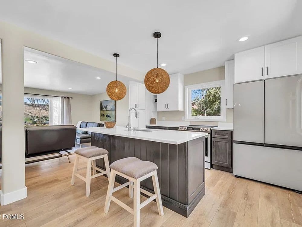 Modern kitchen with island, two pendant lights, and stylish decor in a bright, open space.