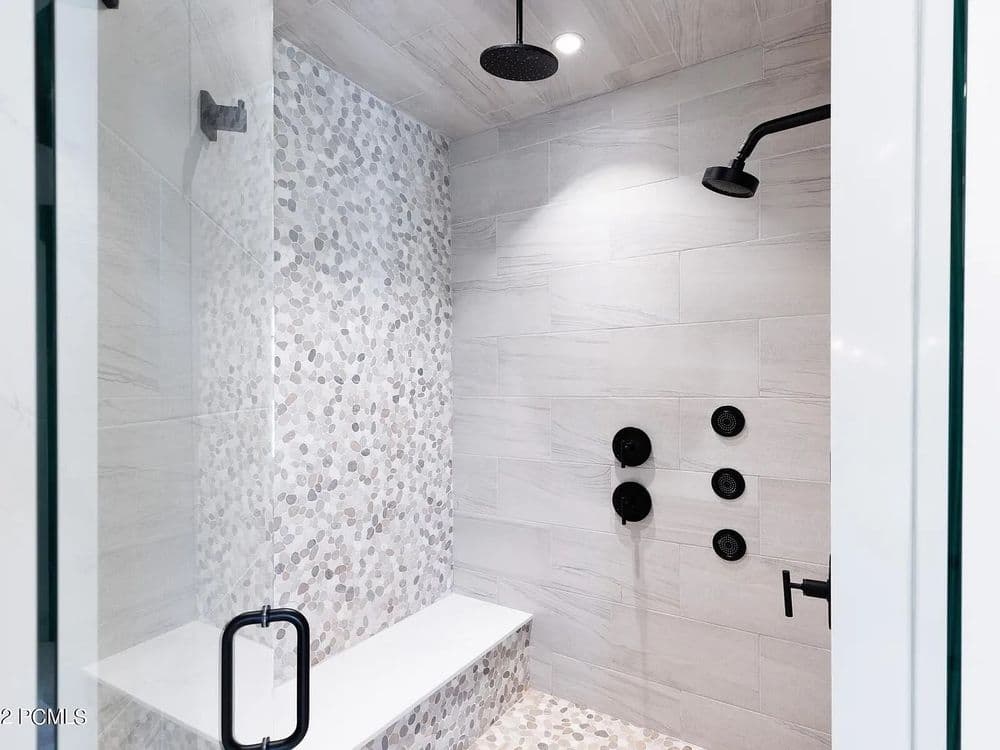 Modern shower design with pebble accent wall, rain showerhead, and sleek fixtures.