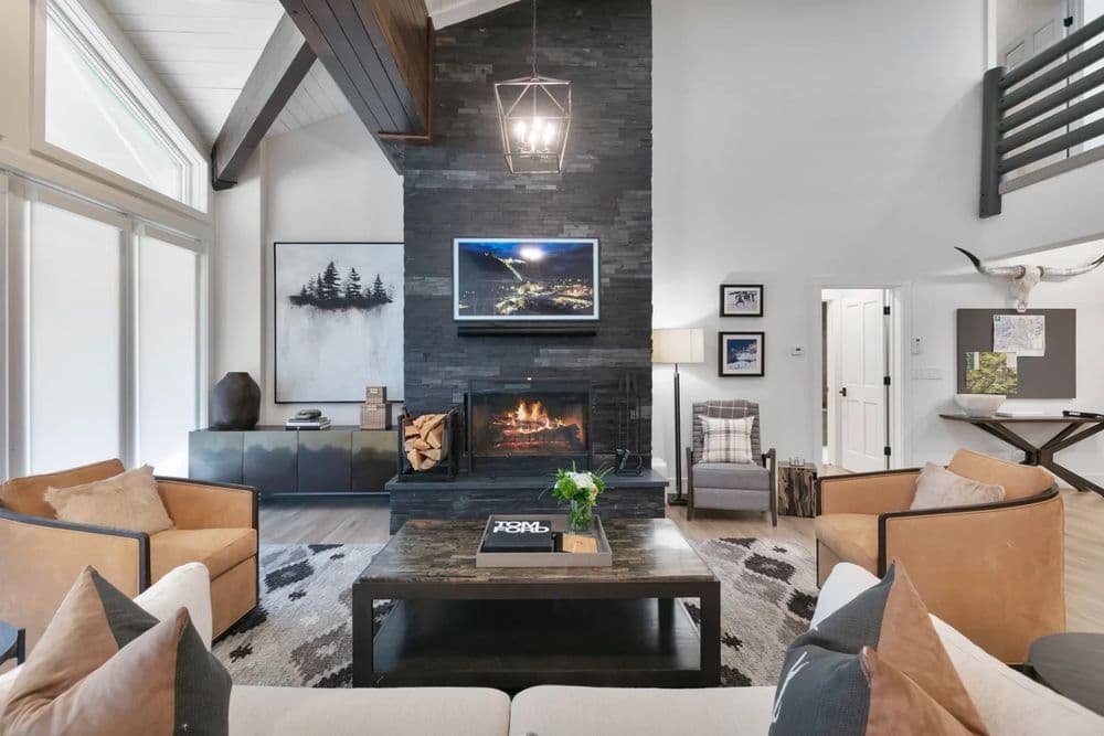 Modern living room with a stone fireplace, cozy seating, and stylish decor elements.