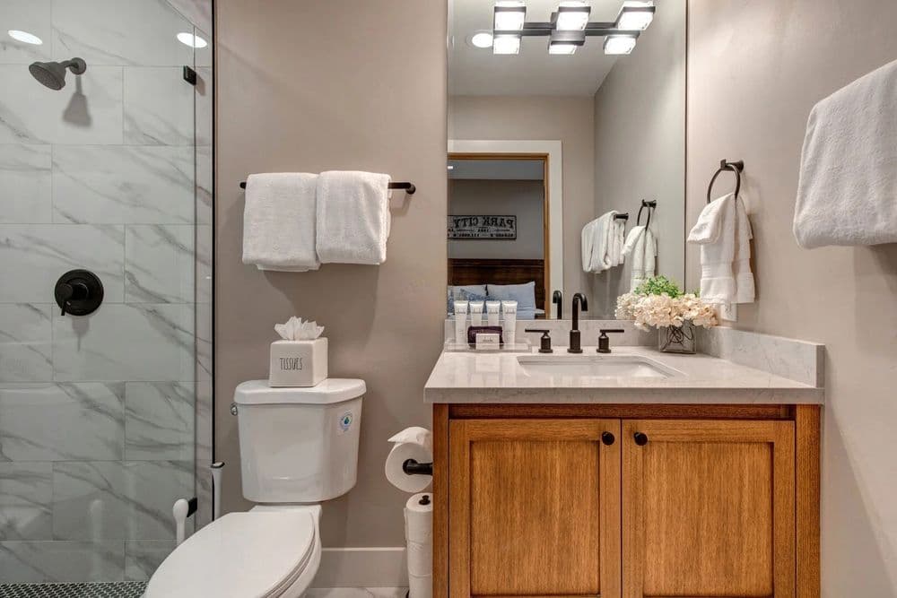 Modern bathroom featuring marble shower, wooden vanity, and stylish decor elements.