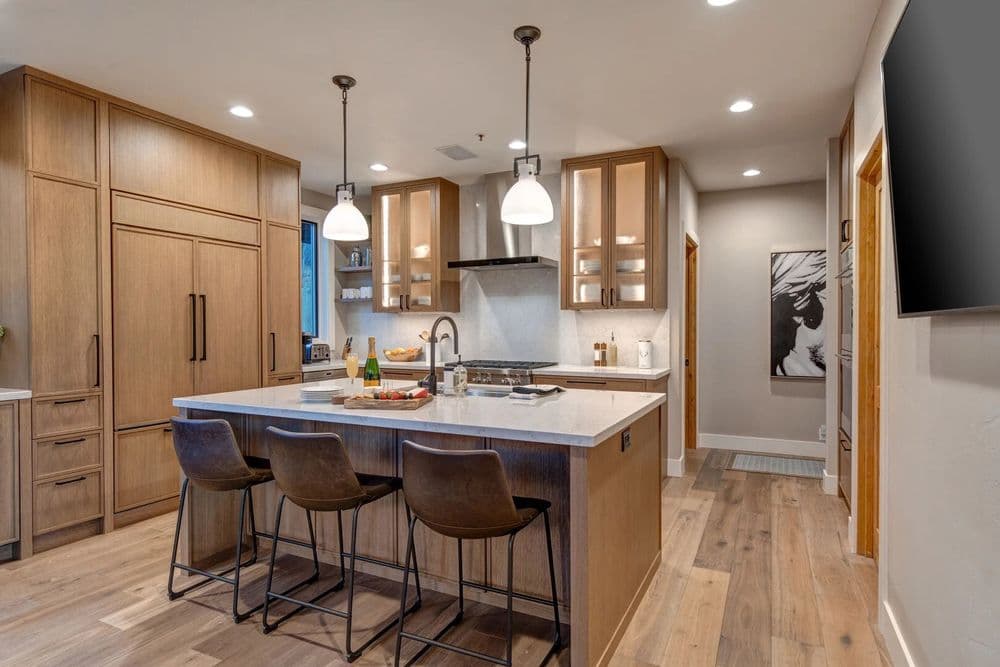 Modern kitchen with wood cabinetry, island seating, and pendant lighting. Warm, inviting design.