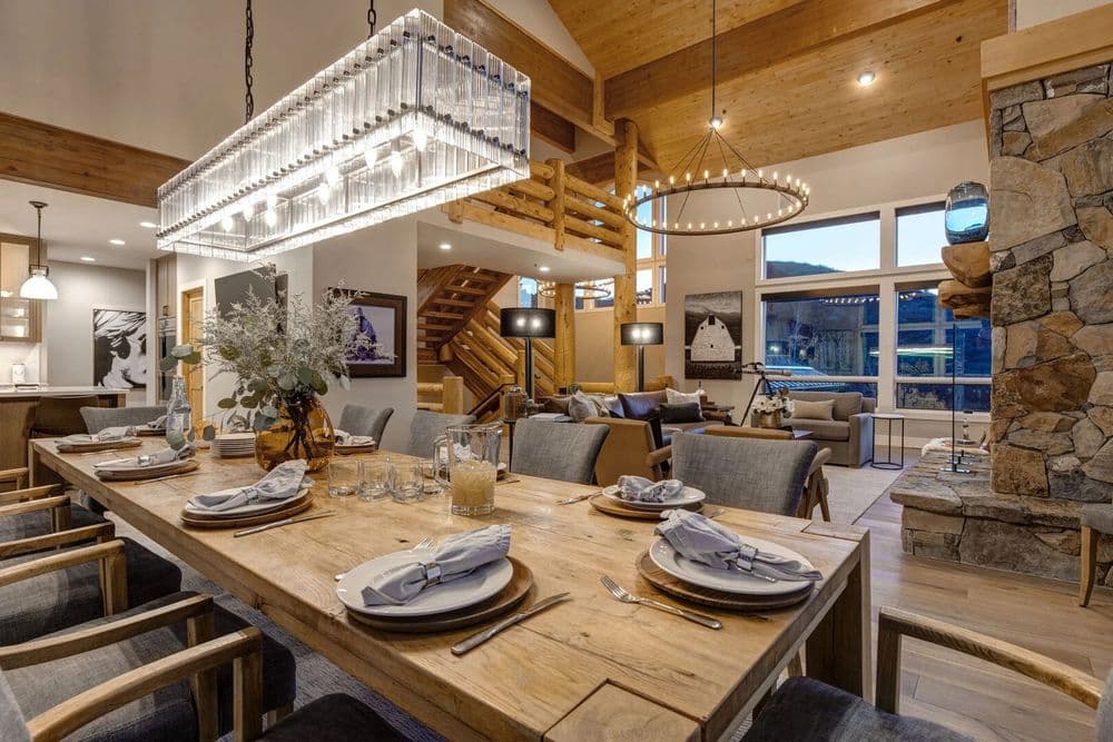 Modern dining room with wooden table, elegant chandelier, and cozy decor in a mountain home.