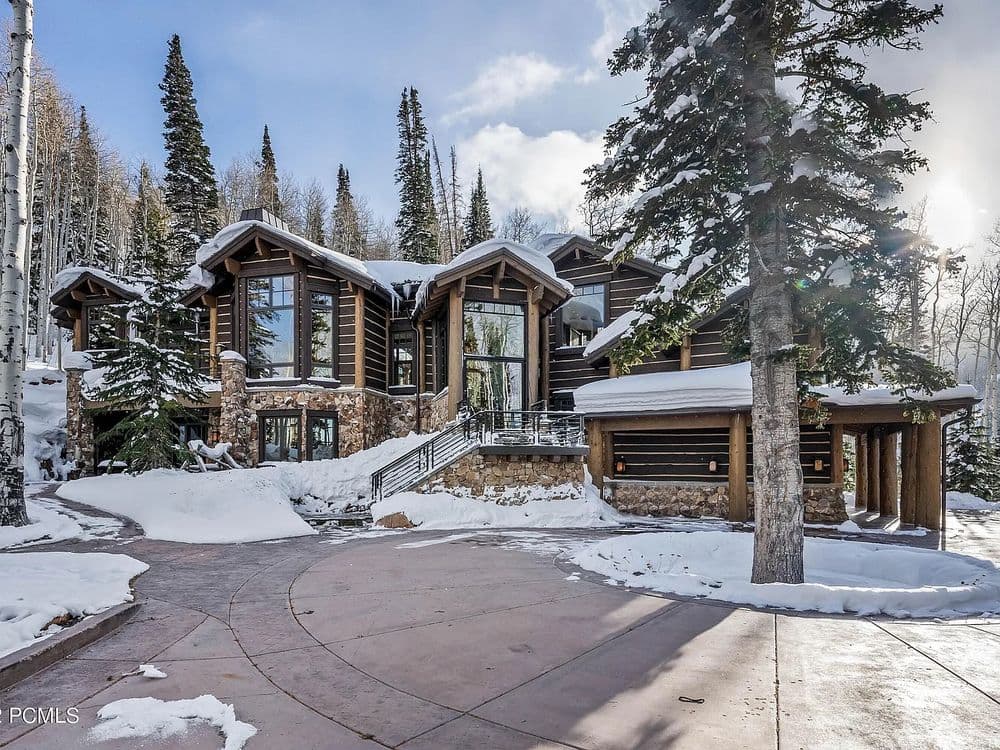 Luxury mountain home surrounded by snow-covered trees and a picturesque landscape.