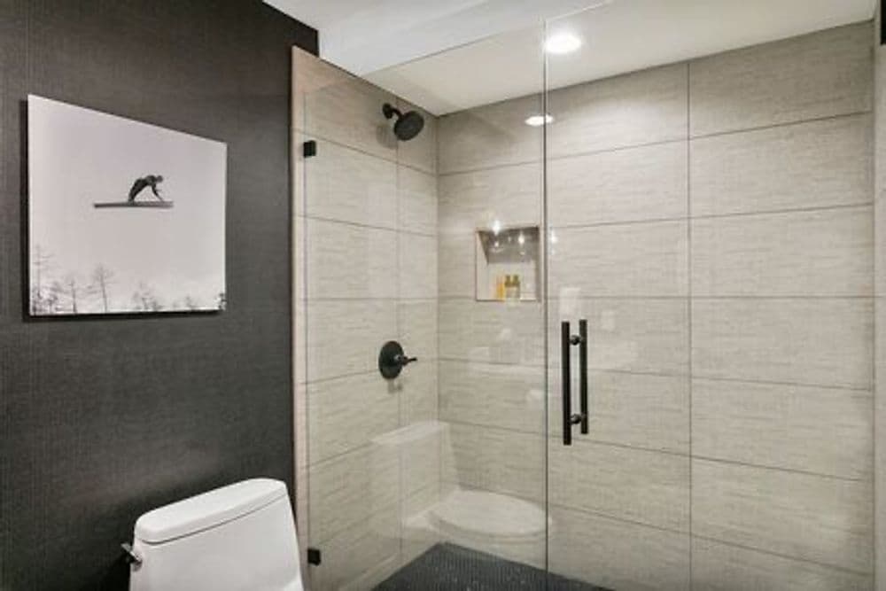 Modern bathroom featuring a glass shower, sleek tiles, and contemporary decor.
