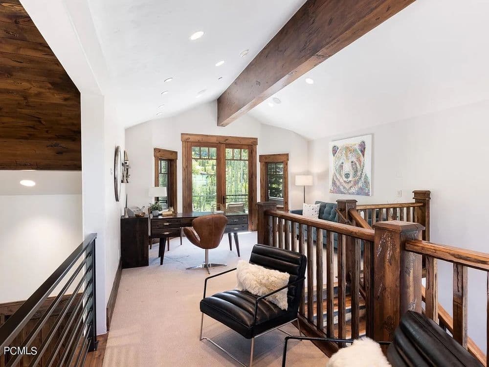 Spacious, modern loft with wooden beams, bear artwork, and cozy seating area.